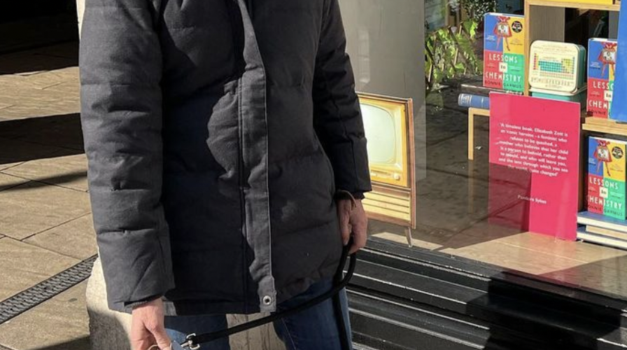 Author Bonnie Garmus outside a bookstore displaying Lessons in Chemistry